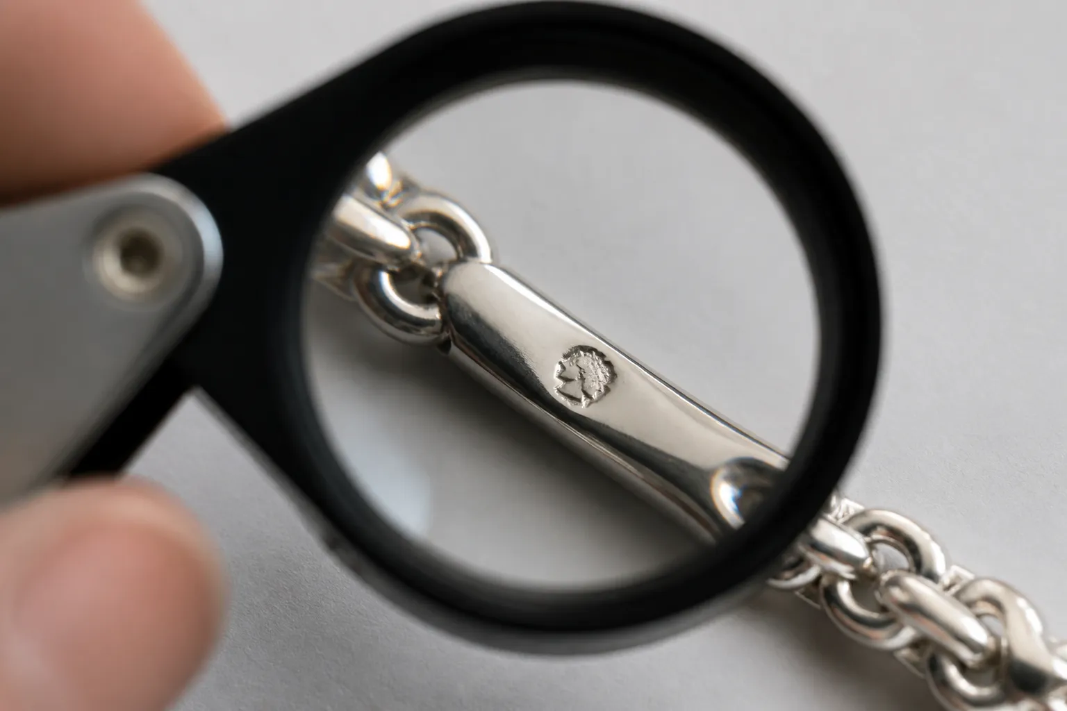 poinçon argent - Gros plan éducatif sur un bracelet en argent 925 montrant la gravure du poinçon officiel sous loupe de joaillier — fond sobre, éclairage studio neutre