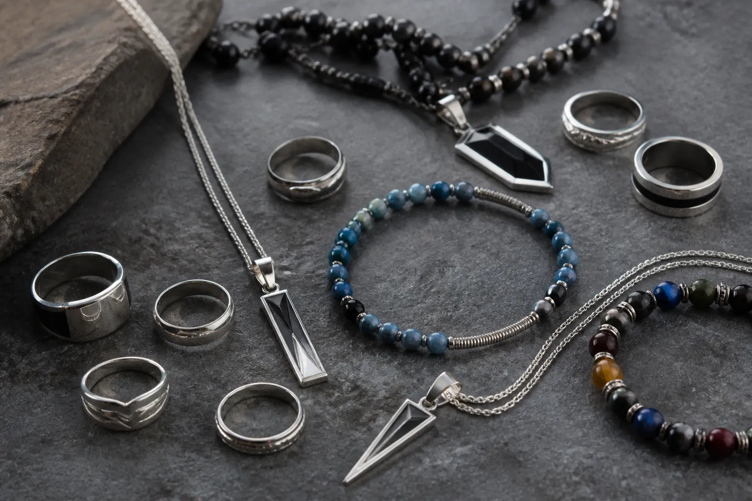 bijoux homme - Photo de planche tendance bijoux homme — collection de bagues empilables, pendentifs géométriques et bracelets en perles de verre colorées, style éditorial de magazine mode