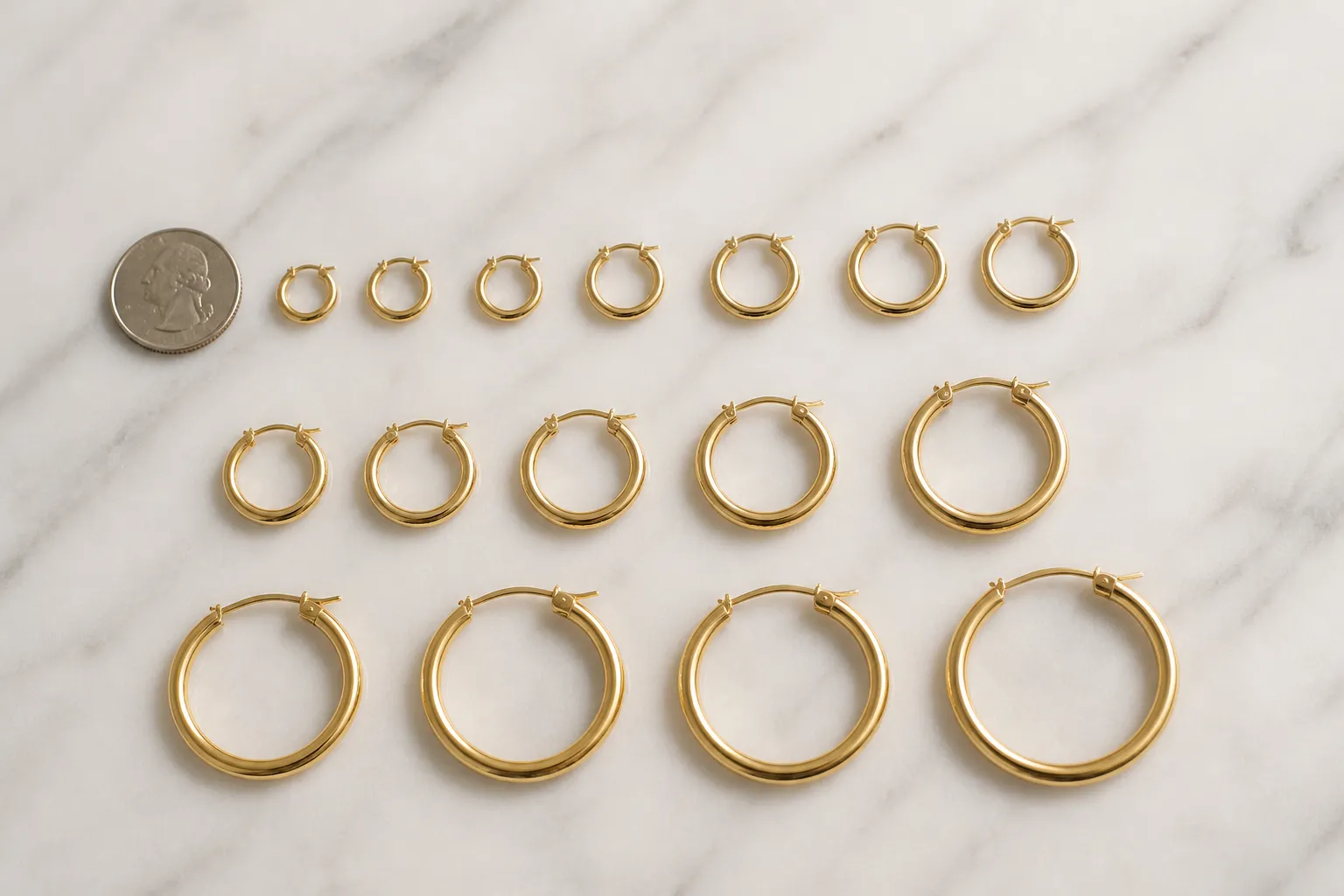 small gold hoop earrings - Flat-lay editorial photo of assorted small gold hoop earrings in 14K and 18K gold vermeil arranged by diameter (10mm, 14mm, 20mm) on a white marble surface with a US quarter coin for scale reference