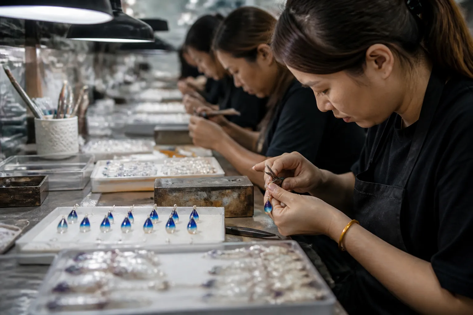 custom jewelry - A Hangzhou workshop production line showing jewelry artisans assembling gradient crystal drop earrings under inspection lighting, with quality control cards visible in the foreground