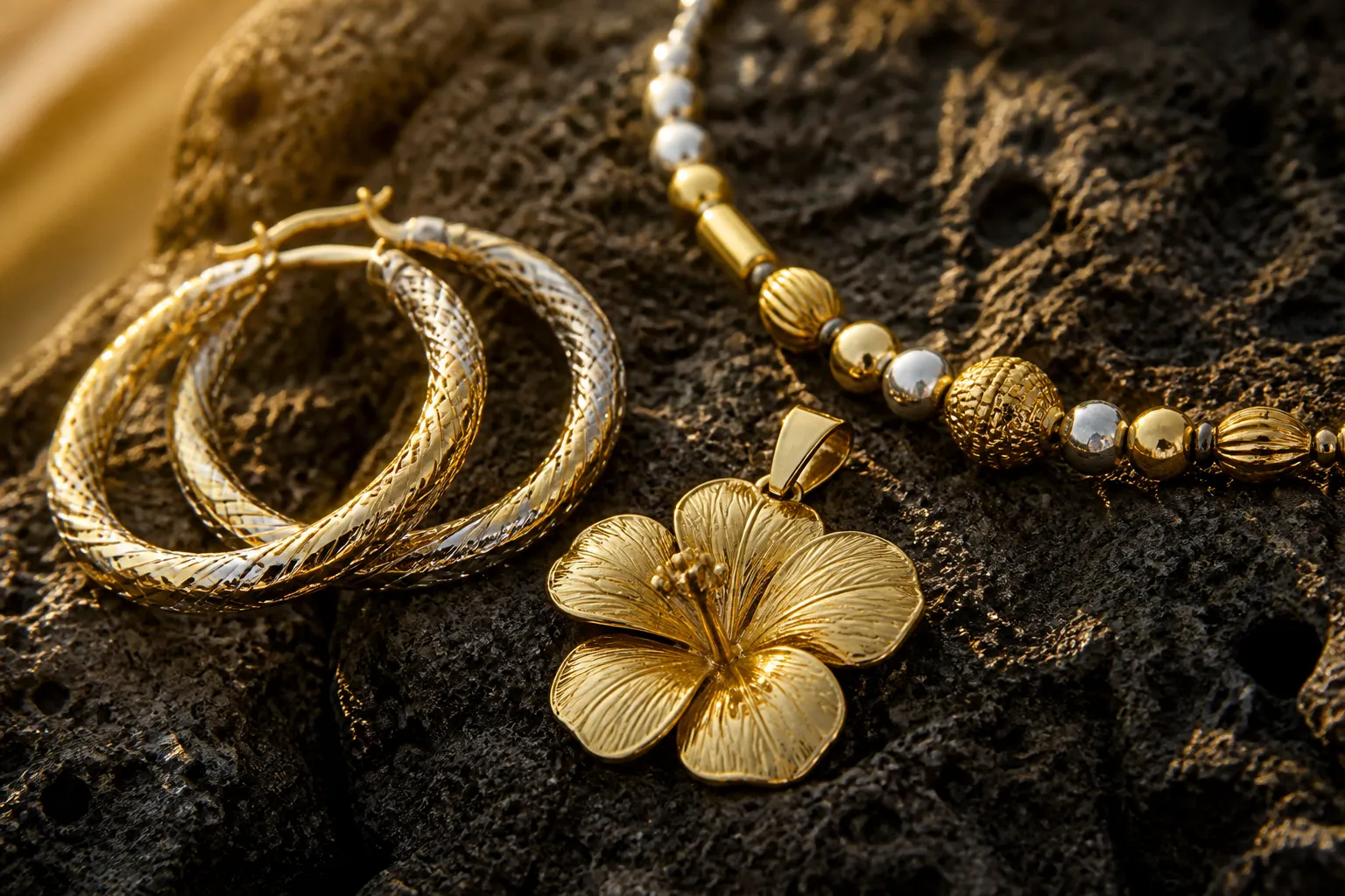 bijoux antillais - Photorealistic close-up of traditional Antillean jewelry pieces laid on natural dark volcanic stone — creole hoop earrings, a hibiscus pendant and a beaded necklace in gold and silver tones, soft warm Caribbean morning light from the left, documentary still-life photography