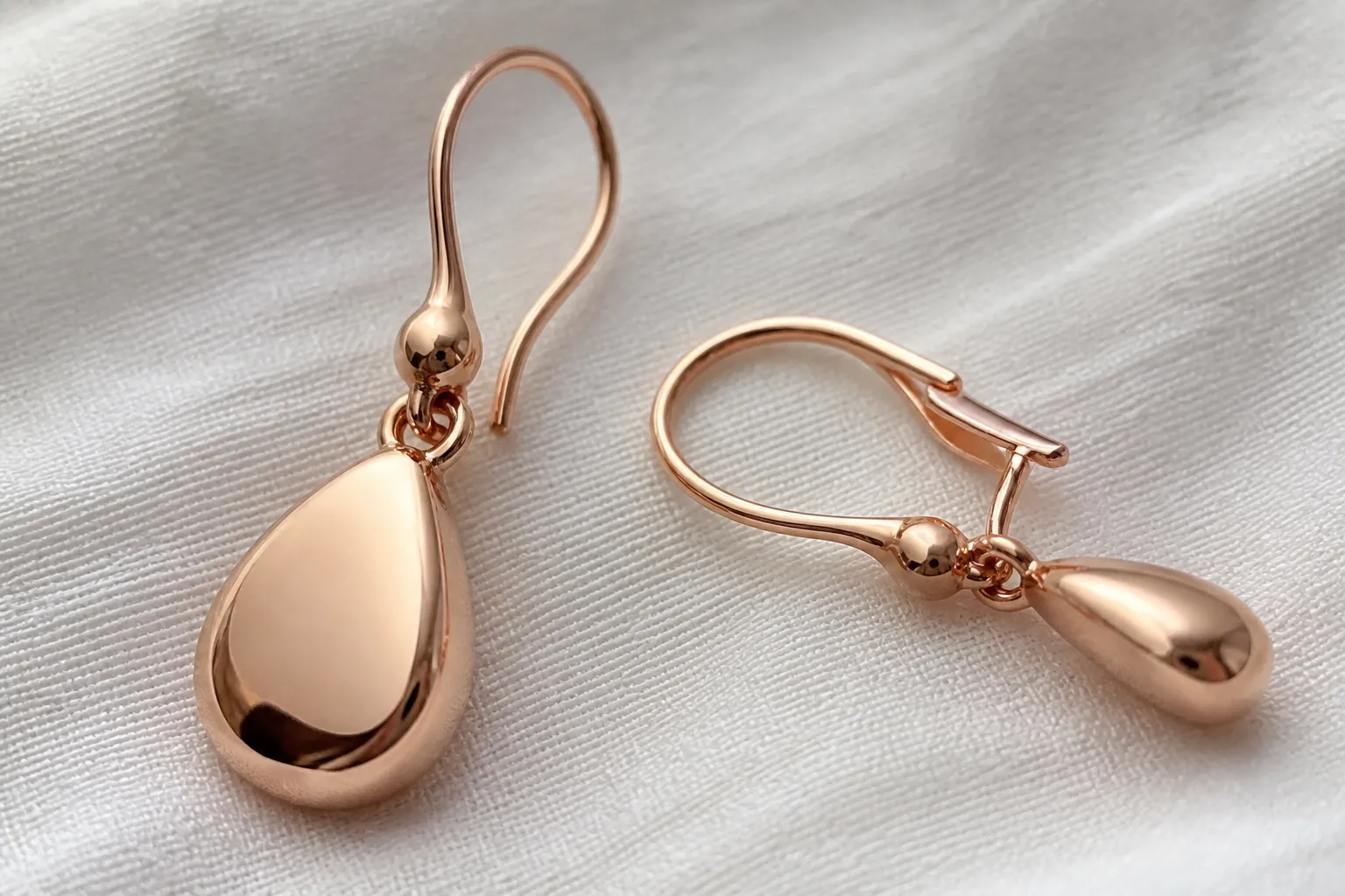 pendientes oro rosa - Foto de detalle de pendientes colgantes oro rosa con cierre tipo gancho francés, mostrando el interior del cierre y el acabado del chapado bajo luz natural —referencia visual útil para evaluar calidad antes de confirmar una muestra