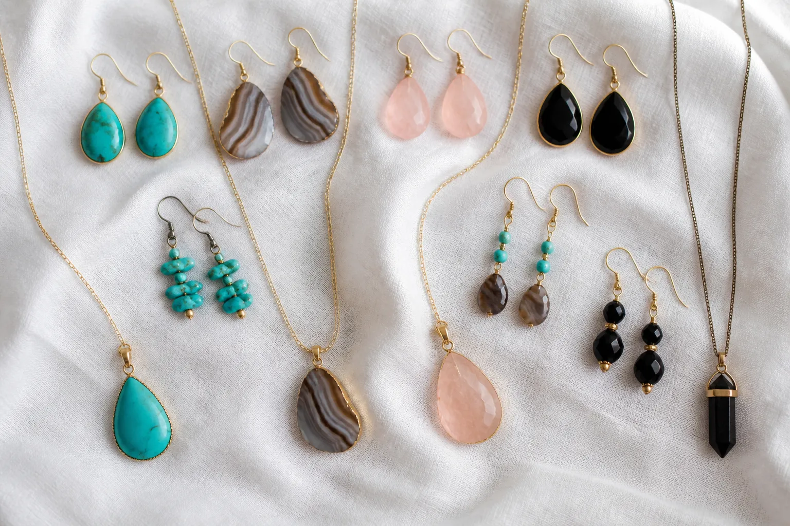 piedra natural - Fotografía editorial de una colección de pendientes y sets de collares con piedras naturales — turquesa, ágata bandeada, cuarzo rosa y obsidiana — sobre fondo de lino blanco, mostrando la variación cromática y textural característica de cada tipo de piedra