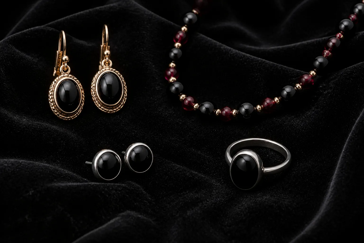 onix piedra - Photorealistic flatlay de cuatro piezas de joyería sobre fondo de terciopelo negro: un par de aretes colgantes con cabujón de ónix negro en montura de cobre dorado, un collar de cuentas de ónix y granate alternadas, un par de studs de ónix redondos en montura de rodio y un anillo de diseño minimalista con ónix ovalado, iluminación de estudio difusa que resalta el brillo vítreo de las piedras