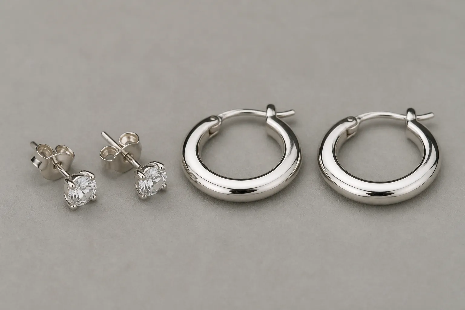 silber kaufen - Detailaufnahme rhodinierter STRAND-Ohrstecker und Creolen im Direktvergleich mit 925er Silberschmuck auf neutralem Hintergrund – zeigt Oberflächenglanz, Farbähnlichkeit und Verarbeitungsqualität