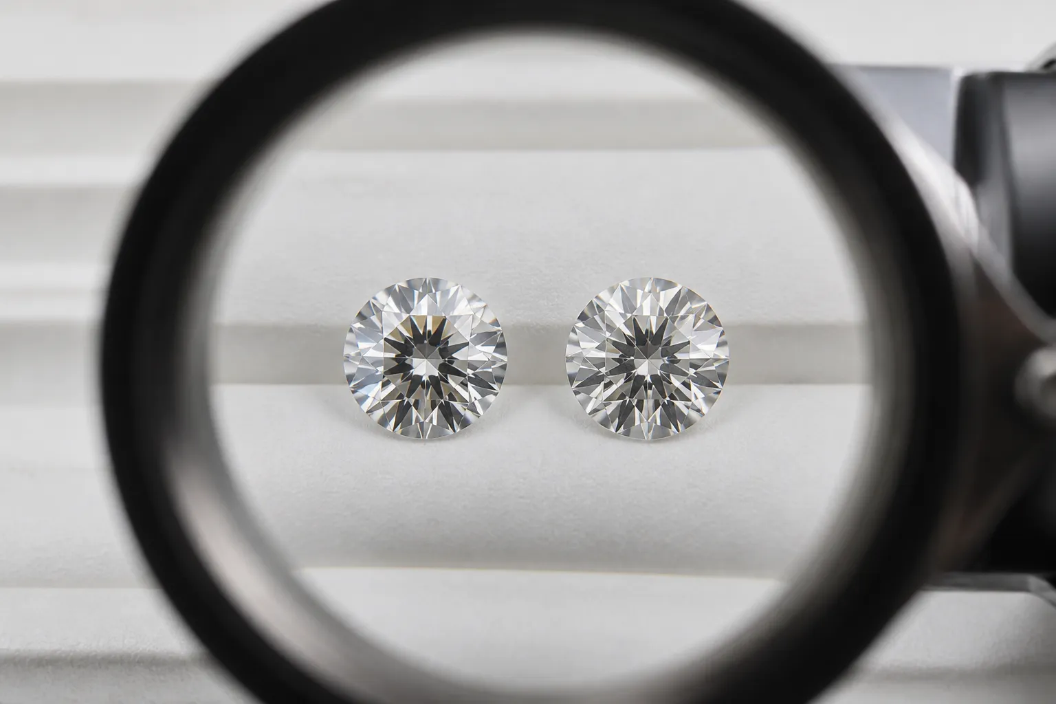 diamant synthétique - Comparaison côte à côte d'un diamant synthétique CVD taillé (grade D/VS1) et d'un diamant naturel de même grade sous loupe gemmologique, avec annotations indiquant les propriétés optiques identiques — indice de réfraction, dureté, dispersion
