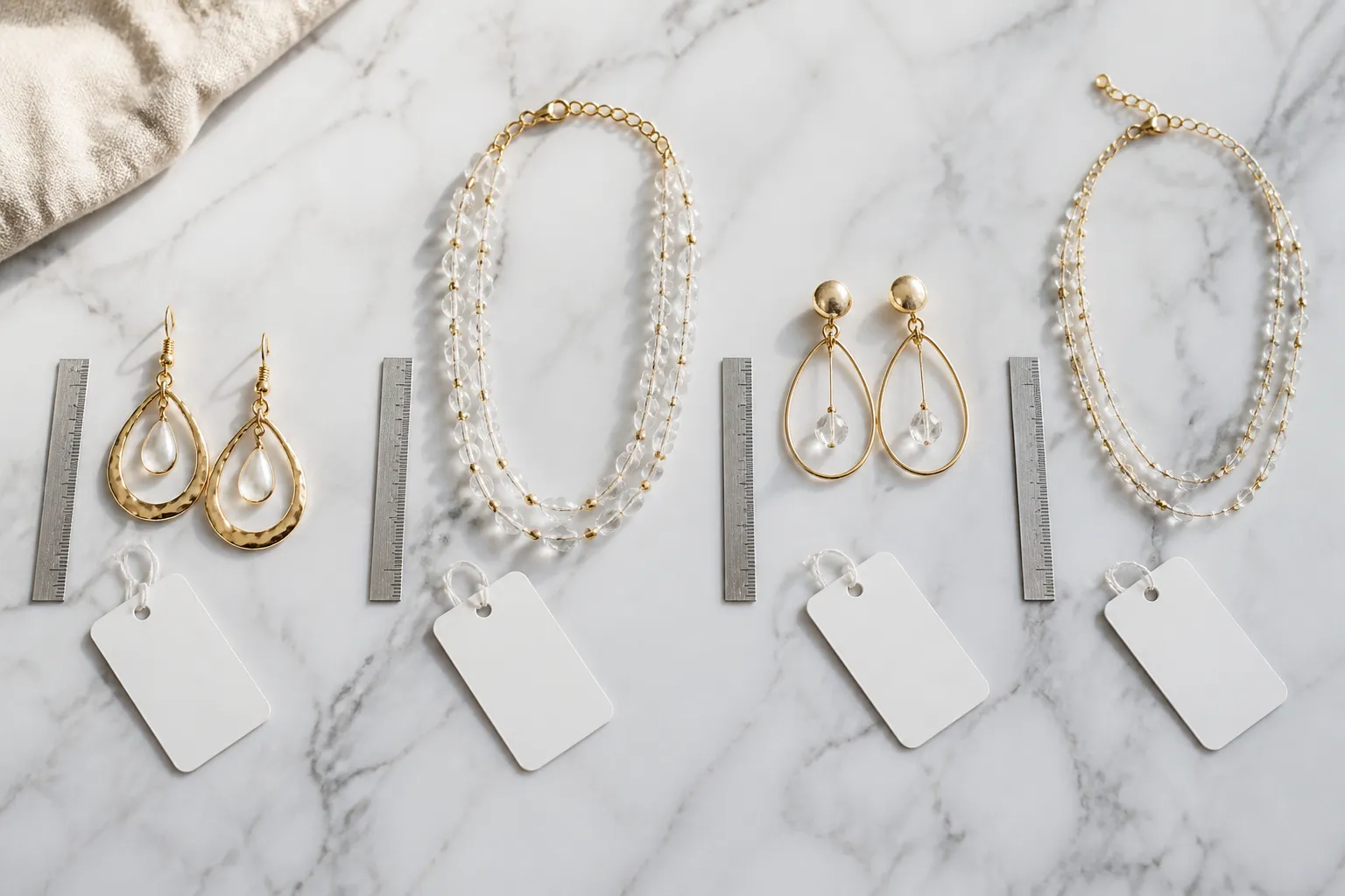 كيف اطلب اغراض من الصين - Editorial flat-lay photo of gold-plated drop earrings and crystal bead necklace sets arranged on a white marble surface, surrounded by quality-inspection tags and a small ruler showing dimensions, warm natural light from above, authentic sourcing/procurement context