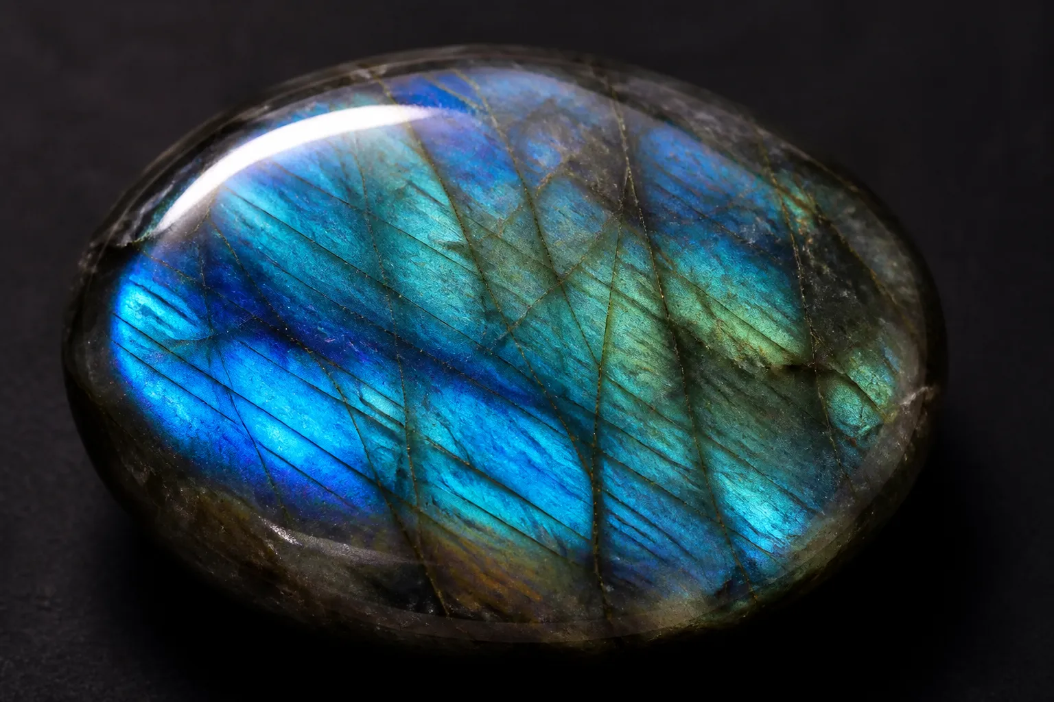 labradorita piedra - Fotografía macro de una labradorita natural pulida mostrando el efecto labradorescencia con destellos azules y verdes sobre fondo oscuro