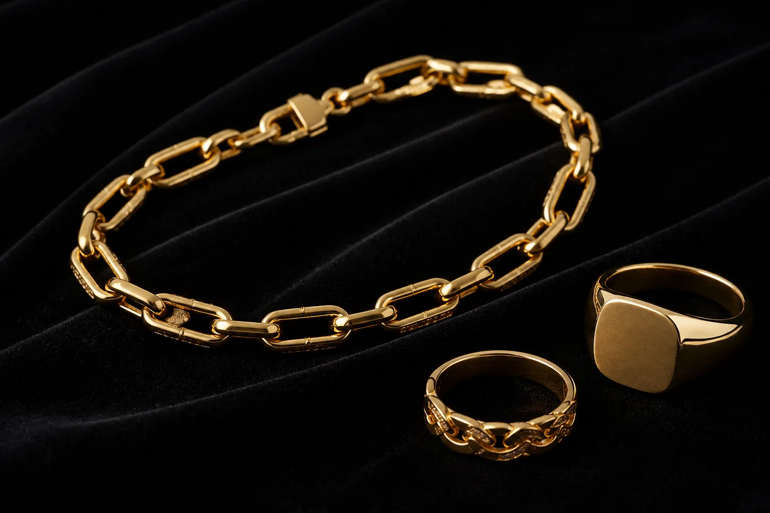 bracelet or - Photographie éditoriale d'un bracelet or 18 carats posé sur velours noir, à côté d'une bague et d'une chevalière — mise en scène bijouterie haut de gamme, lumière studio