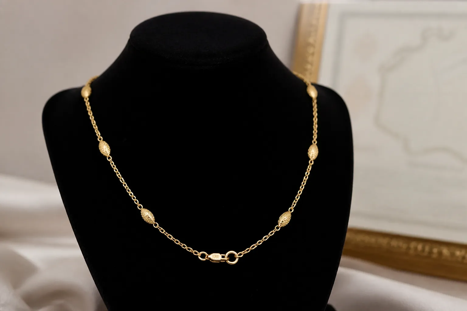 collier or femme - Photographie éditoriale d'un collier en or jaune 18 carats sur présentoir velours, avec poinçon visible et certificat d'authenticité en arrière-plan