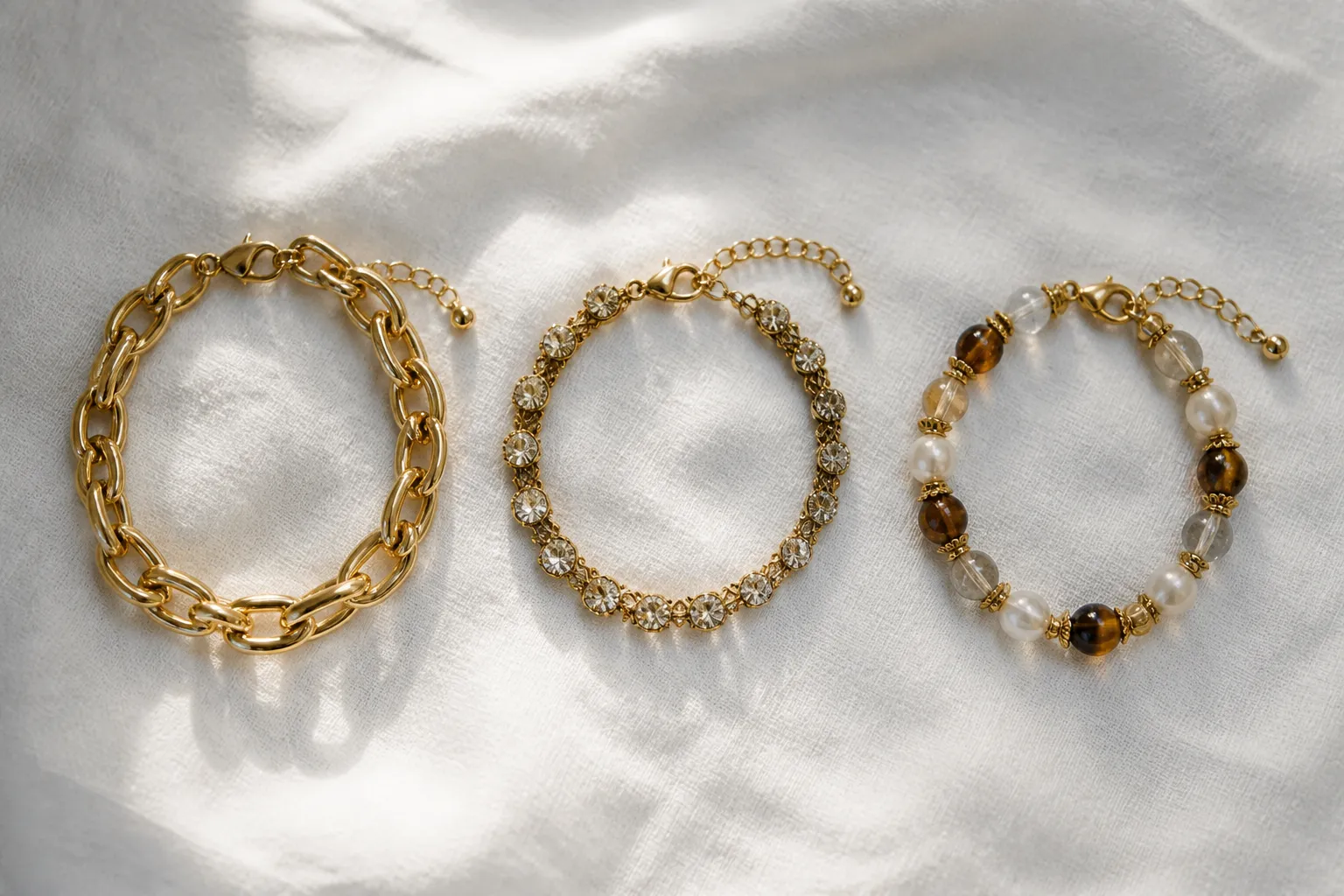 bracelet or femme - Assortiment côte à côte : un bracelet chaine en or jaune massif, un bracelet plaqué or avec cristaux vintage, un bracelet en perles de verre bicolores — contraste de texture, de finition et de coloris pour illustrer la diversité des alternatives