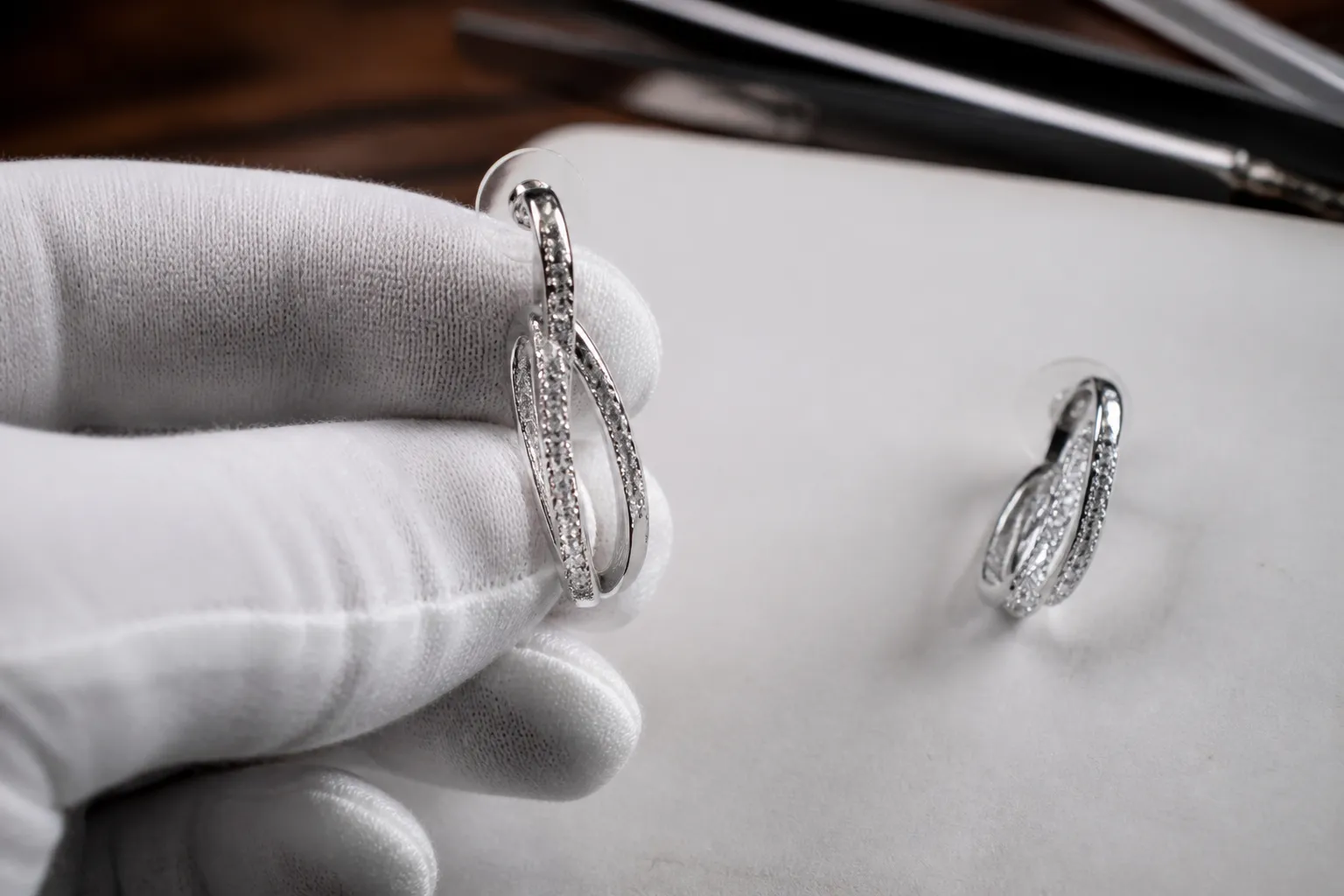 joyería burgos - Fotografía editorial de primer plano mostrando la textura y el brillo de pendientes STRAND con acabado en rodio y cristales, destacando los detalles de calidad que se verifican en la inspección QC
