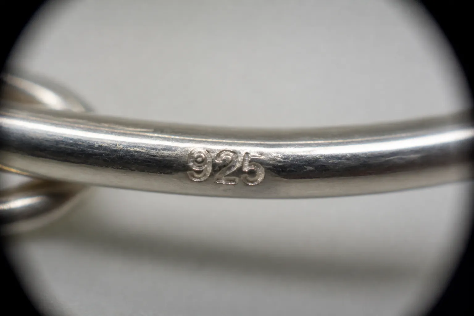 ohrringe silber 925 - Nahaufnahme eines eingestempelten „925"-Hallmarks auf einem Ohrringhaken unter Lupenvergrößerung – gut lesbare Prägung, klare Metallstruktur zur Veranschaulichung des Reinheitsnachweises