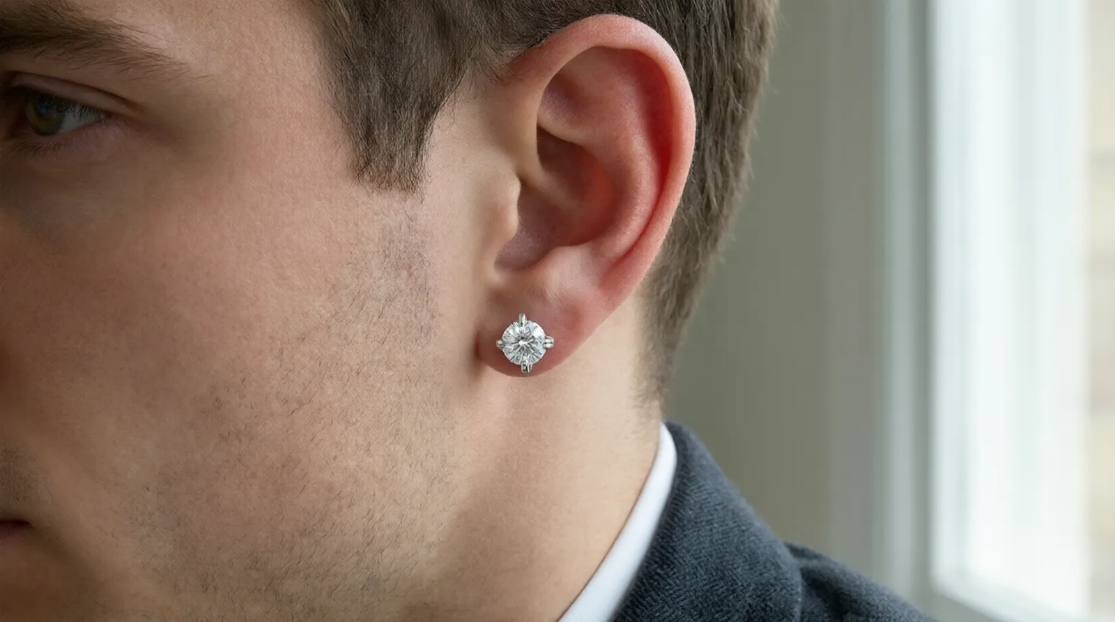 pendientes hombre diamante - Imagen editorial de un hombre llevando un pendiente stud de diamante en oro blanco, con foco en el detalle del engaste — contexto de moda masculina contemporánea para ilustrar el producto en uso real