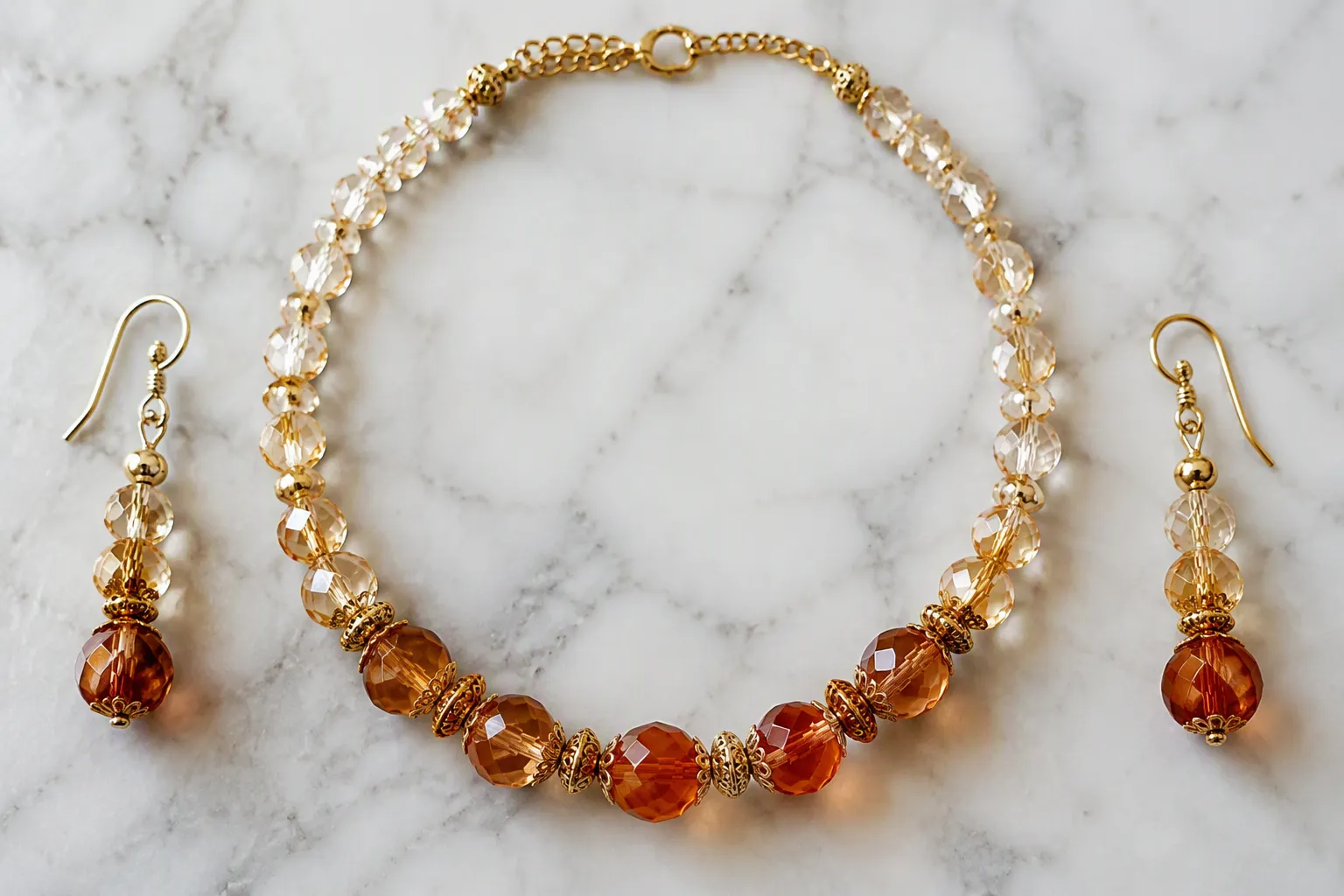 joyería bisutería - Foto editorial de un conjunto collar y pendientes en cristal degradado y cuentas de vidrio de dos tonos, estilo vintage, sobre superficie de mármol blanco, mostrando detalle de textura y brillo del acabado bañado en oro