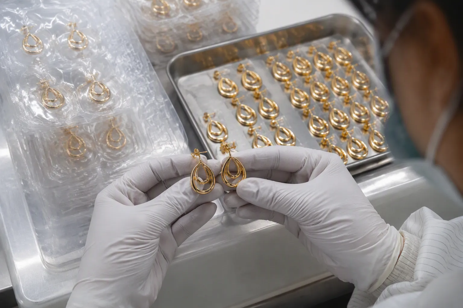 custom jewelry - Factory QC floor showing gold-plated copper earring pairs being inspected under bright lighting before shipment packaging
