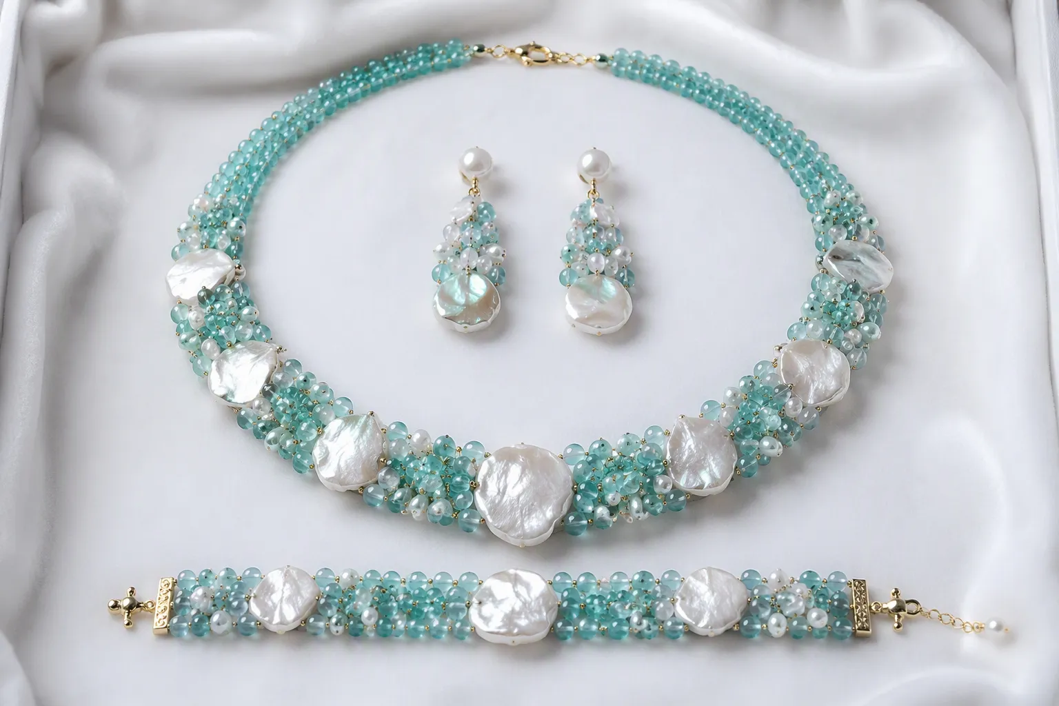 parure bijoux - Photographie éditoriale d'une parure bijoux complète — collier ras-de-cou, boucles d'oreilles pendantes et bracelet assortis en perles de verre turquoise et nacre, présentés sur velours blanc avec étiquettes de référence produit visibles