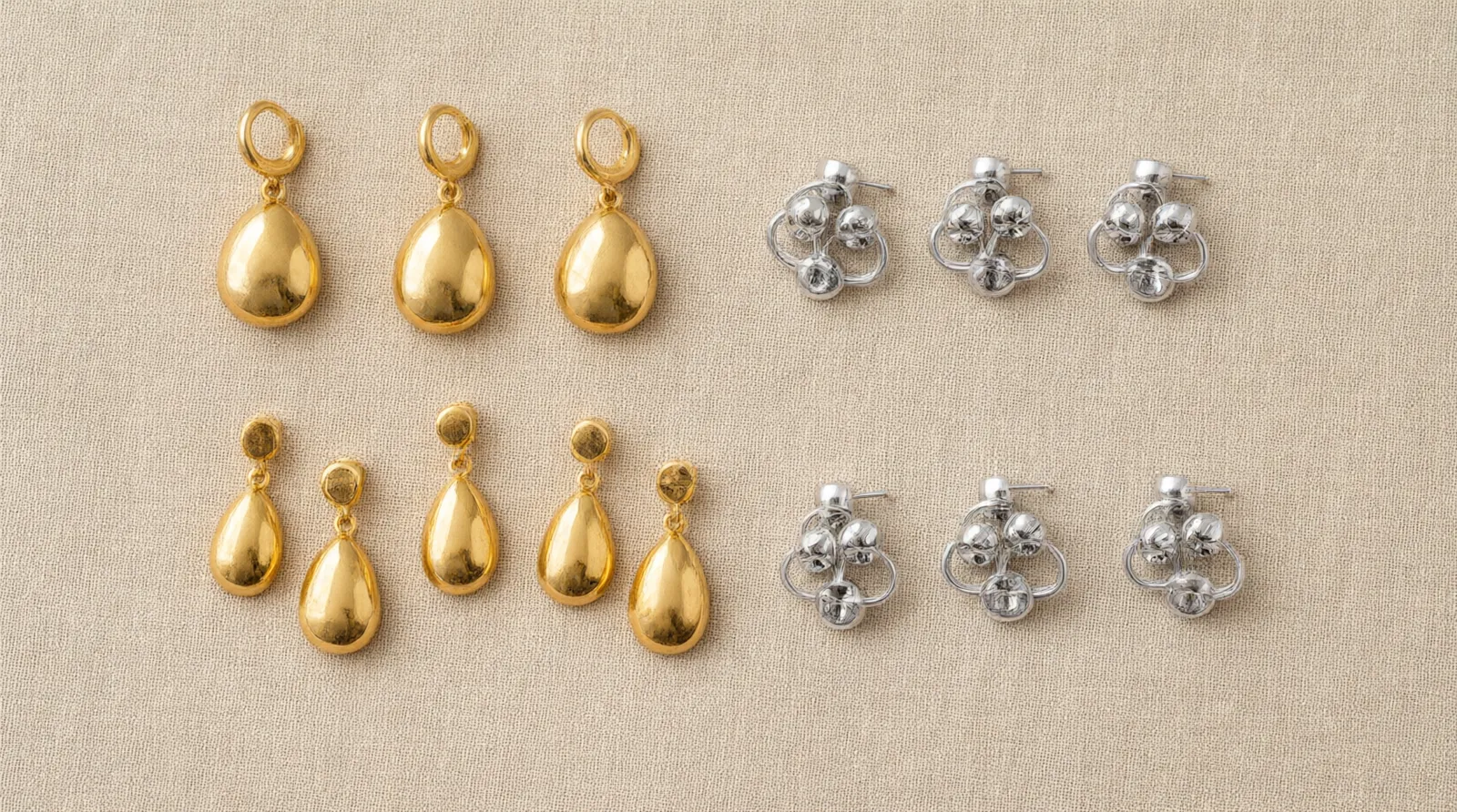 custom jewelry - Flat-lay of gold-plated drop earrings and rhodium-plated stud earring sets arranged by finish type on a neutral surface, showing catalog range and the contrast between two-tone and single-finish variants relevant to buyers evaluating style breadth