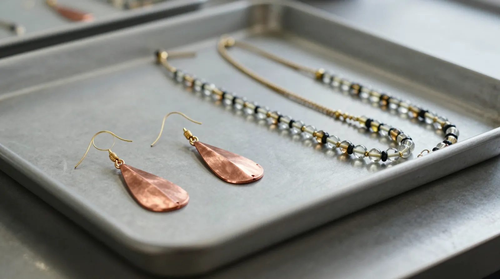bijoux femme pas cher - Photographie éditoriale montrant un étalage de boucles d'oreilles pendantes en cuivre plaqué or et de colliers à perles de verre bicolores, organisés sur des plateaux de contrôle qualité dans un atelier de fabrication à Hangzhou, illustrant la diversité d'un catalogue de 114 styles.